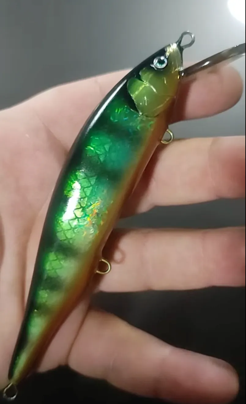 Handmade 12 cm Twitch lure with holographic perch finish, held in hand